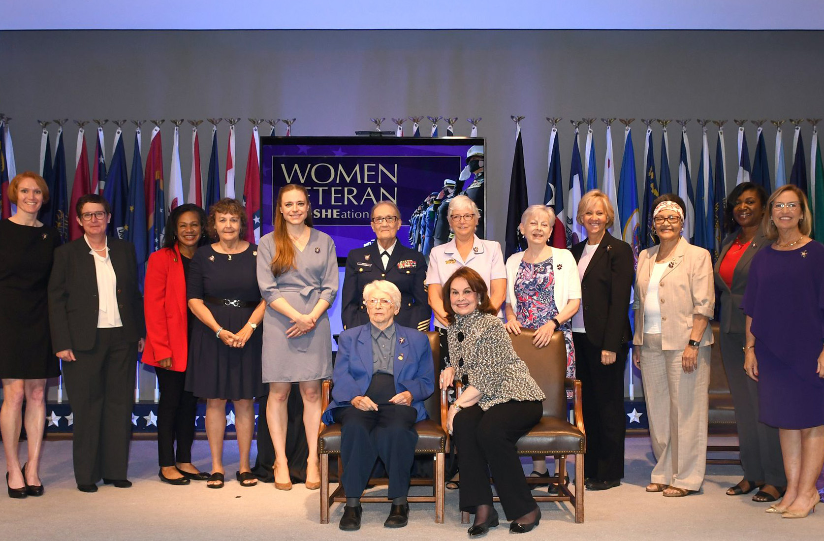 Jewelry designer Ann Hand (bottom right) sits with military women gifted with her new brooch at the Military Women’s Memorial, June 12, 2021. This date coincides with the 73rd anniversary of the Women’s Armed Services Integration Act, which enabled military women to join the active duty component of each branch of service. It is also recognized as Women Veterans Day by some U.S. states. Women veterans representing the enlisted and commissioned ranks of each military branch were given the brooch to wear as a symbol of their selfless service. The brooch is designed in the shape of a forget-me-not flower, colored purple to represent all the services. The “V” on each leaf represents the valor of America’s servicewomen and the pearl in the center represents the purity of their mission.